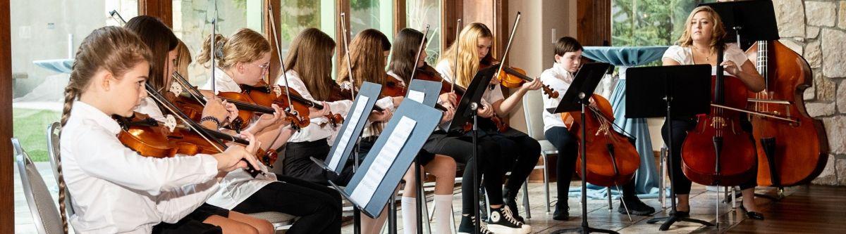 A group of Parker Performing Arts students and a teacher play strings together.