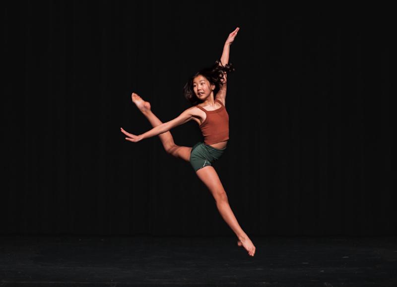 Parker Performing Arts dance student in mid-leap during a stage performance.